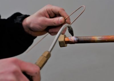 Photo de mains d'homme faisant une brasure sur un tuyau en cuivre